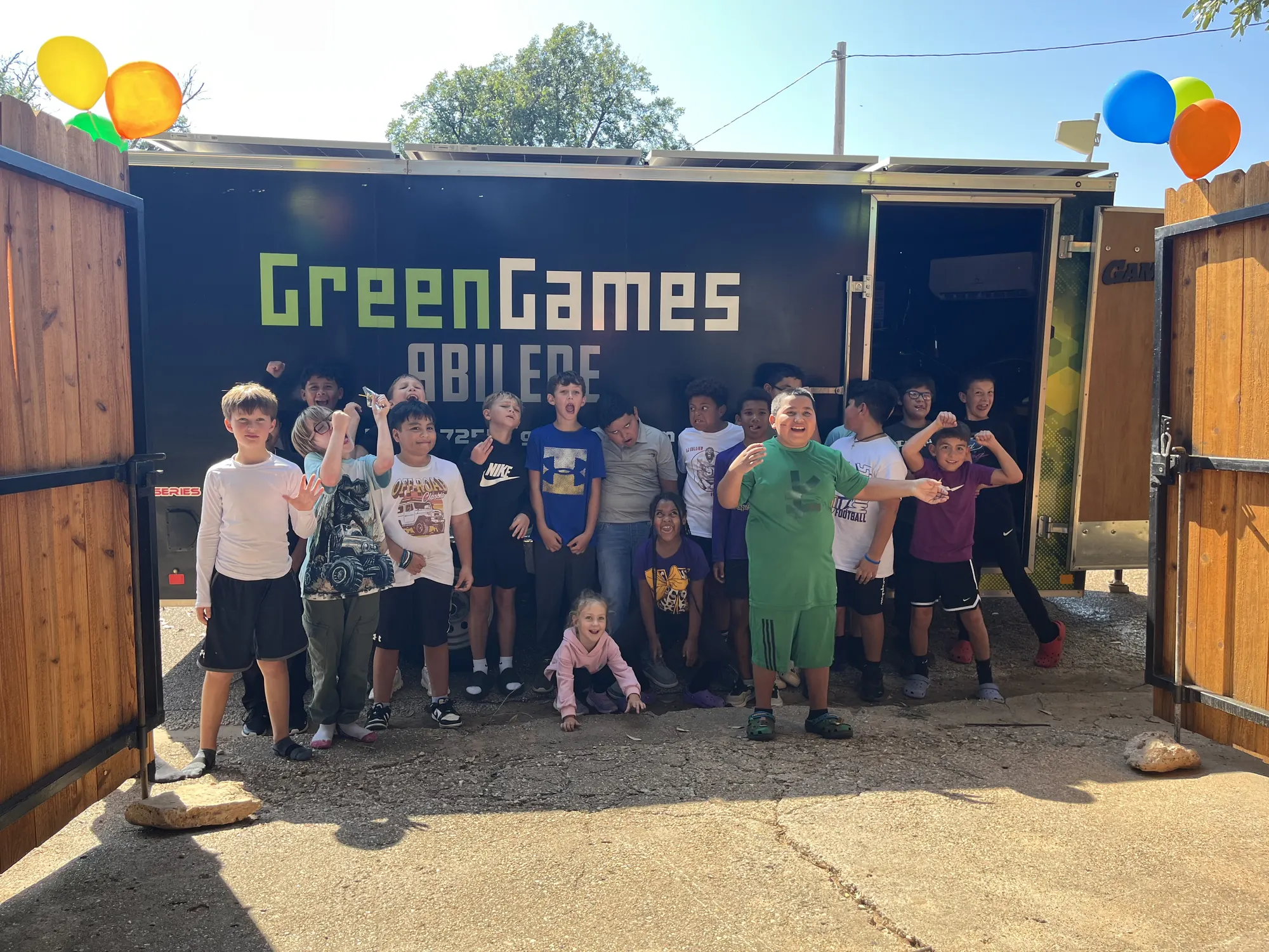 Birthday party guests smiling together in front of the Green Games Abilene trailer