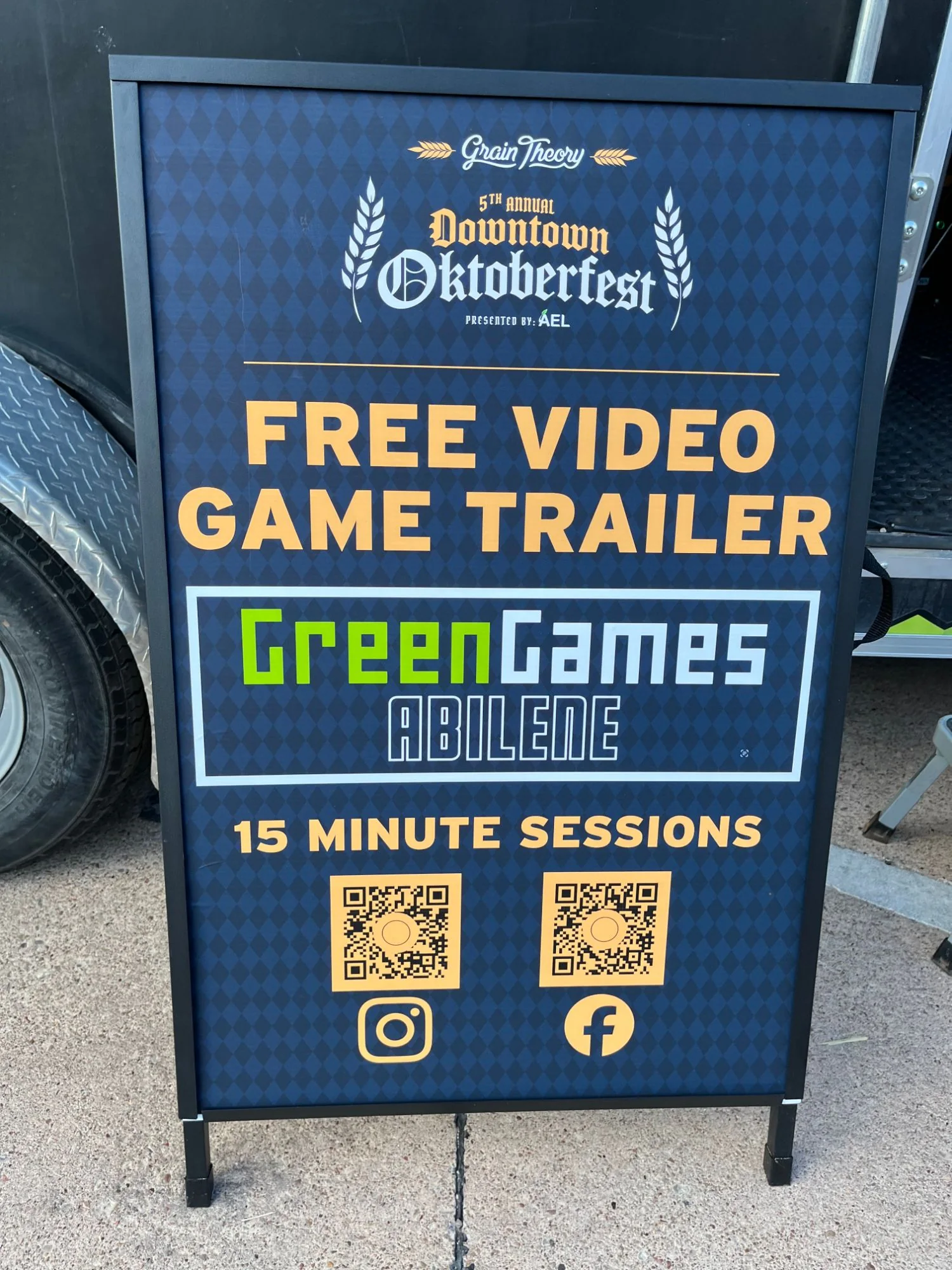Downtown Oktoberfest sidewalk sign reading “Free video game trailer” with the full-color Green Games Abilene logo on a dark navy background